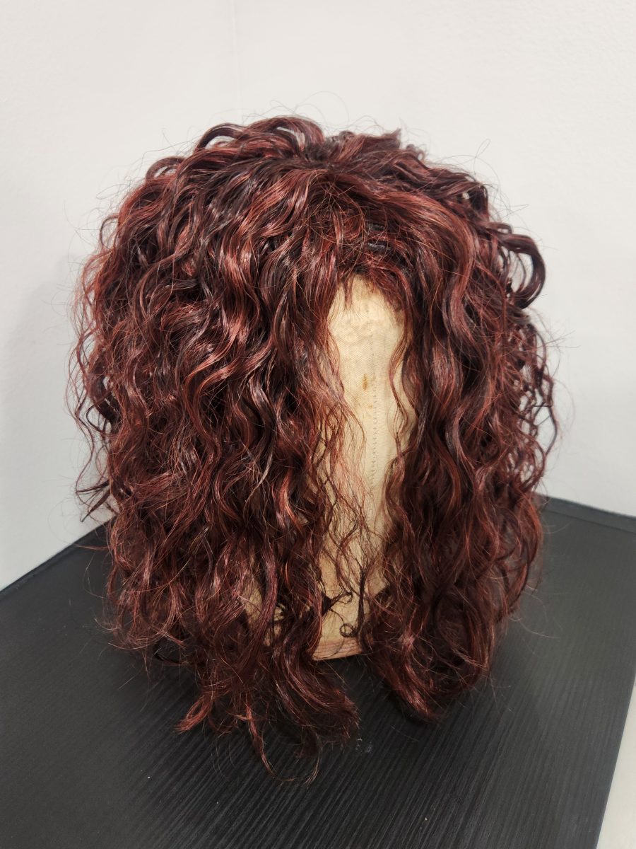 Side view of a burgundy-toned wig with thick spiral waves and curls by Siobhan Rozinski at K Bella Hair Studio & Spa in Brighton, MI