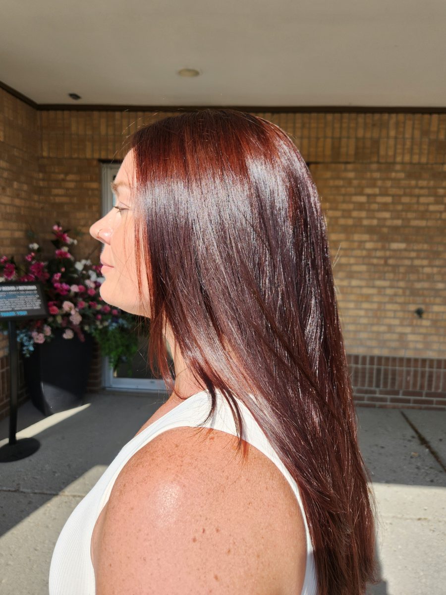 Side view of long burgundy hair in natural outdoor lighting showing depth and texture by Siobhan Rozinski at K Bella Hair Studio & Spa in Brighton, MI
