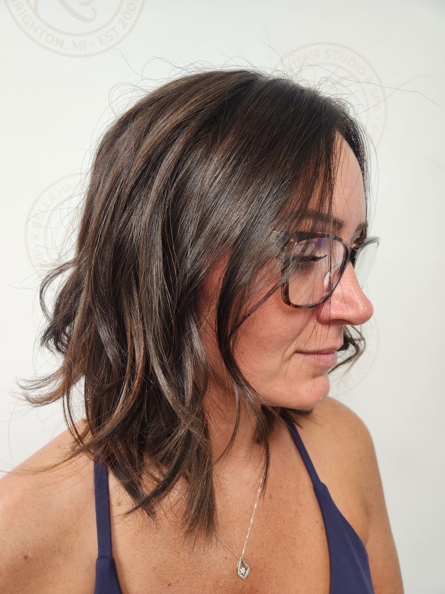 Side profile of shoulder-length brunette hair with rooty lowlights and face-framing layers by Siobhan Rozinski at K Bella Hair Studio & Spa in Brighton, MI