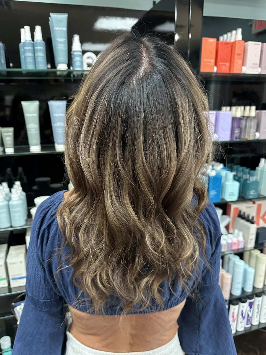 Back view of long wavy hair with blended root shadow and warm blonde highlights by Liberty Greenwood at K Bella Hair Studio & Spa in Brighton, MI