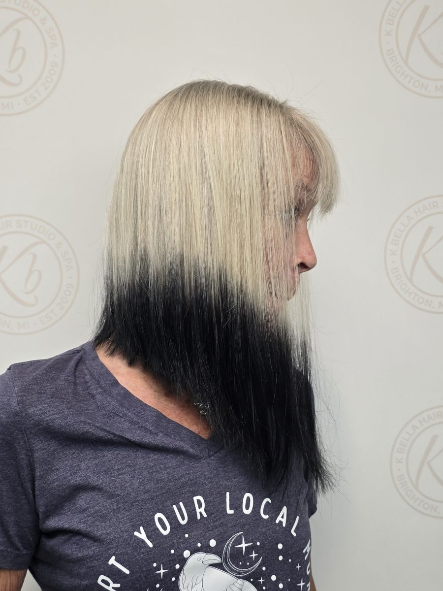 Side profile of a steep angled bob with silver-blonde hair at the crown fading to black at the ends, by Kristan Sayers at K Bella Hair Studio & Spa in Brighton, MI