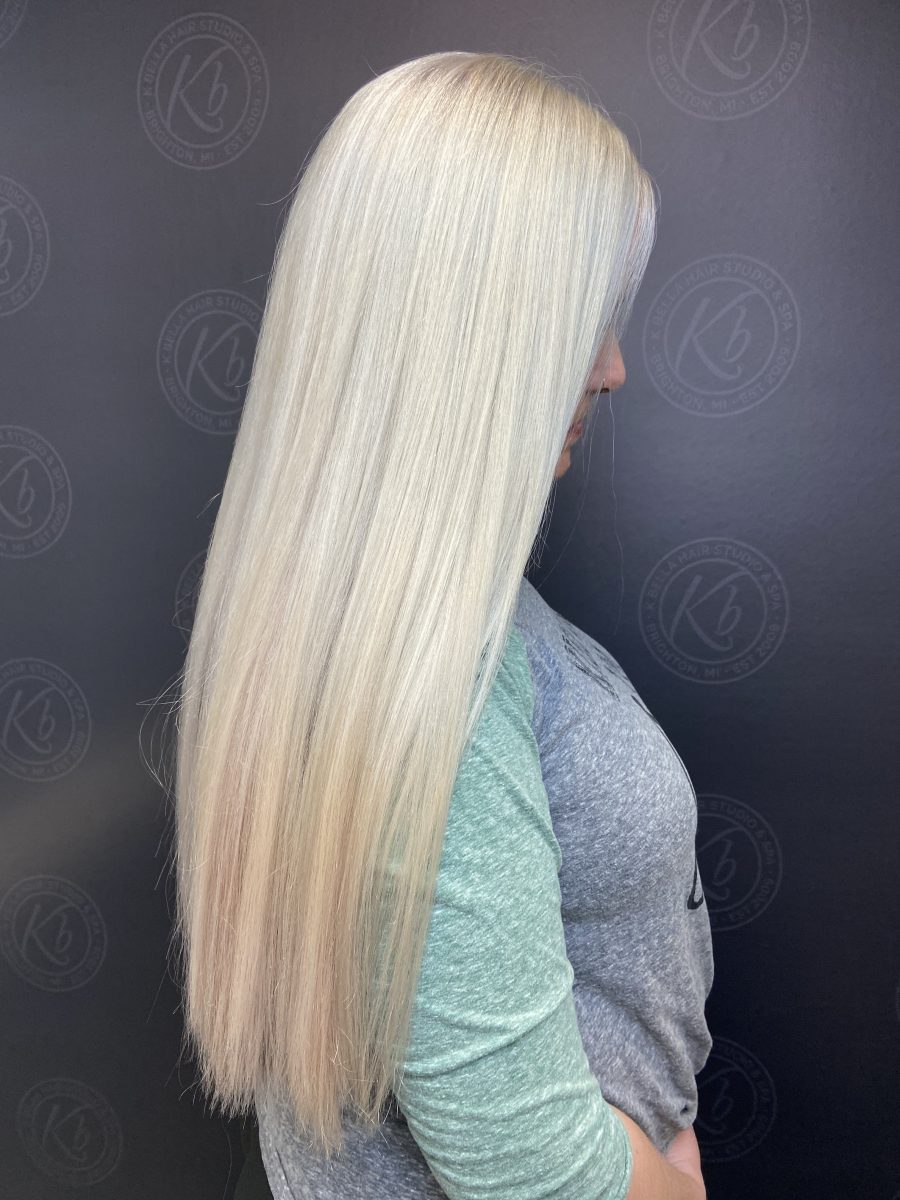 Long bleached blonde hair shown from the side, mid-length view by Kameryn Bell at K Bella Hair Studio & Spa in Brighton, MI