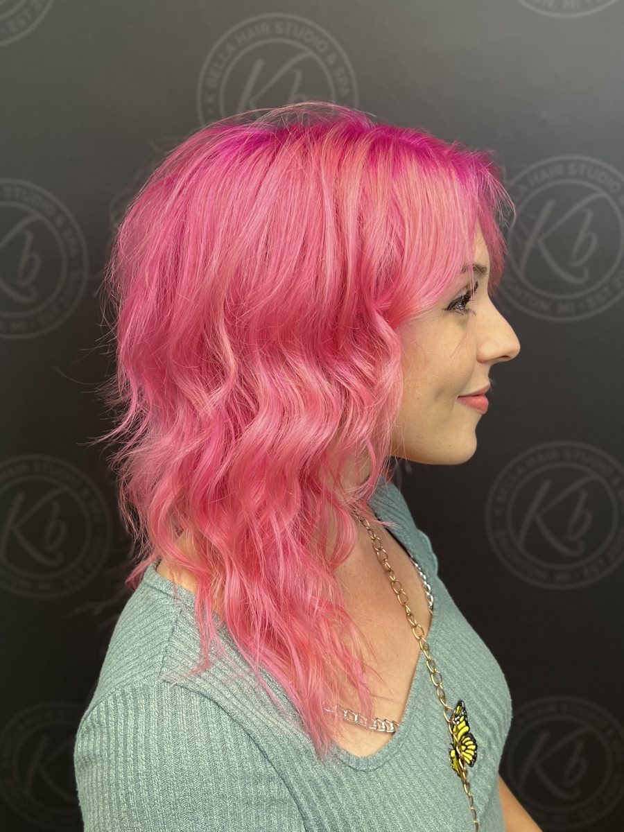 Side profile of shoulder-length pink wavy hair with darker roots by Raquel Vettese at K Bella Hair Studio & Spa in Brighton, MI