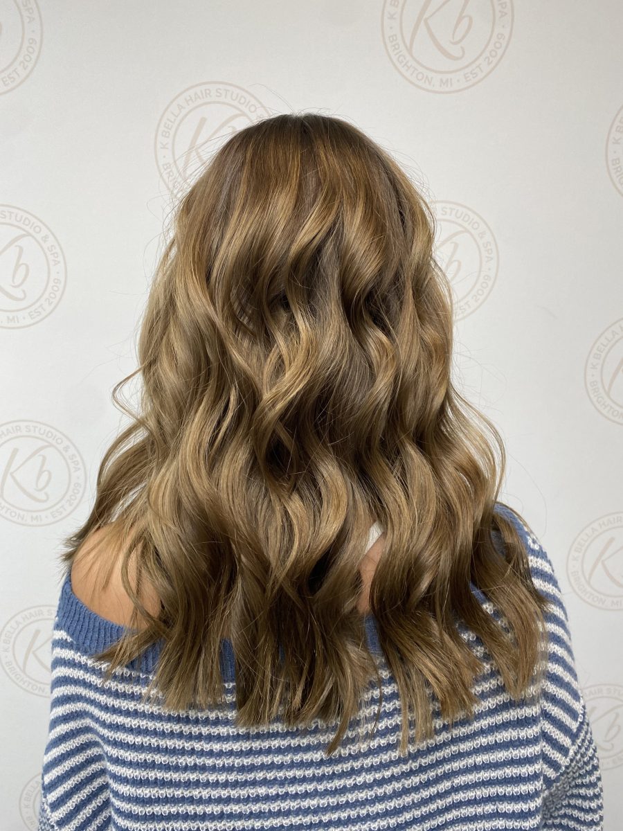 Back view of long wavy hair with caramel blonde balayage highlights by Abbey French at K Bella Hair Studio & Spa in Brighton, MI